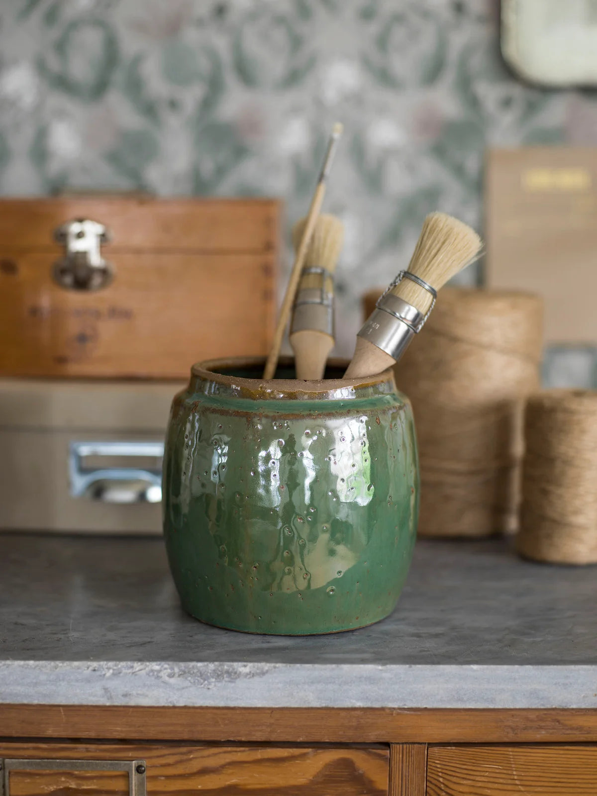 Behang met plantmotief van bladeren THISTLE gedempt groen met roze en beige