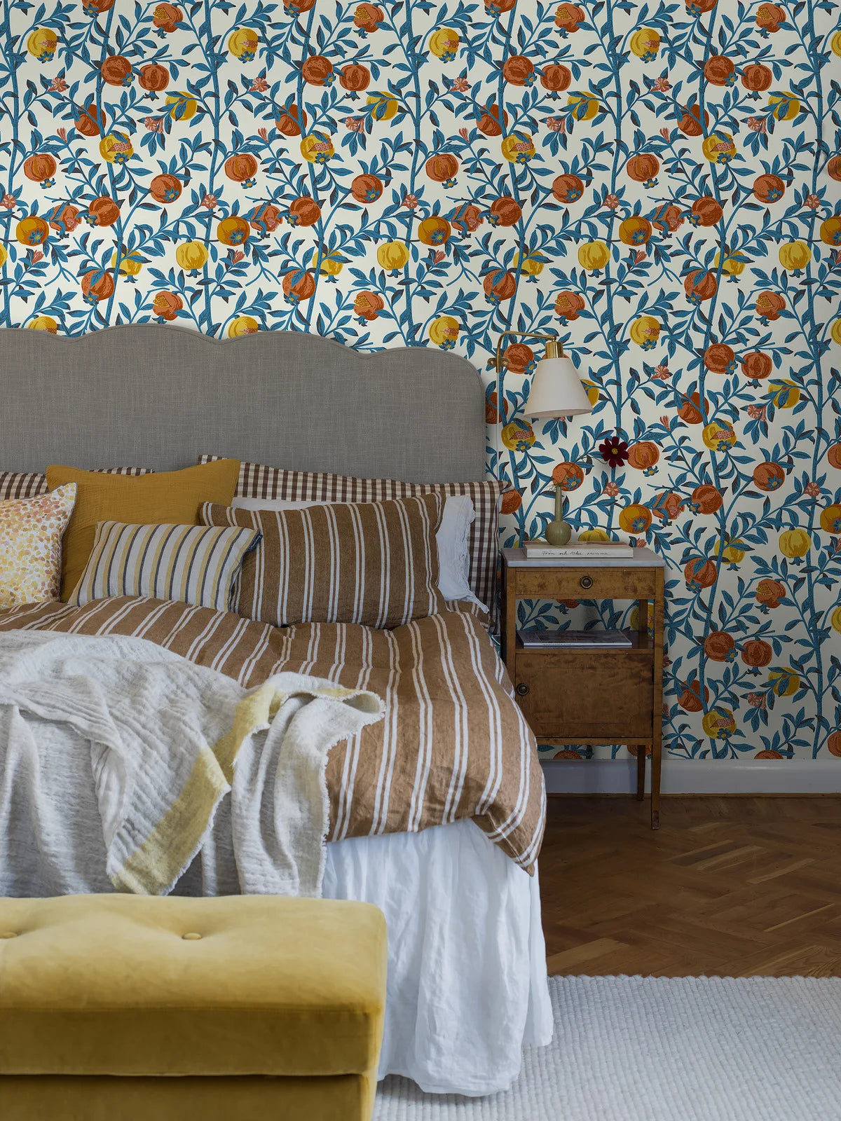 Wallpaper with a botanical pattern of pomegranates in white with blue and orange