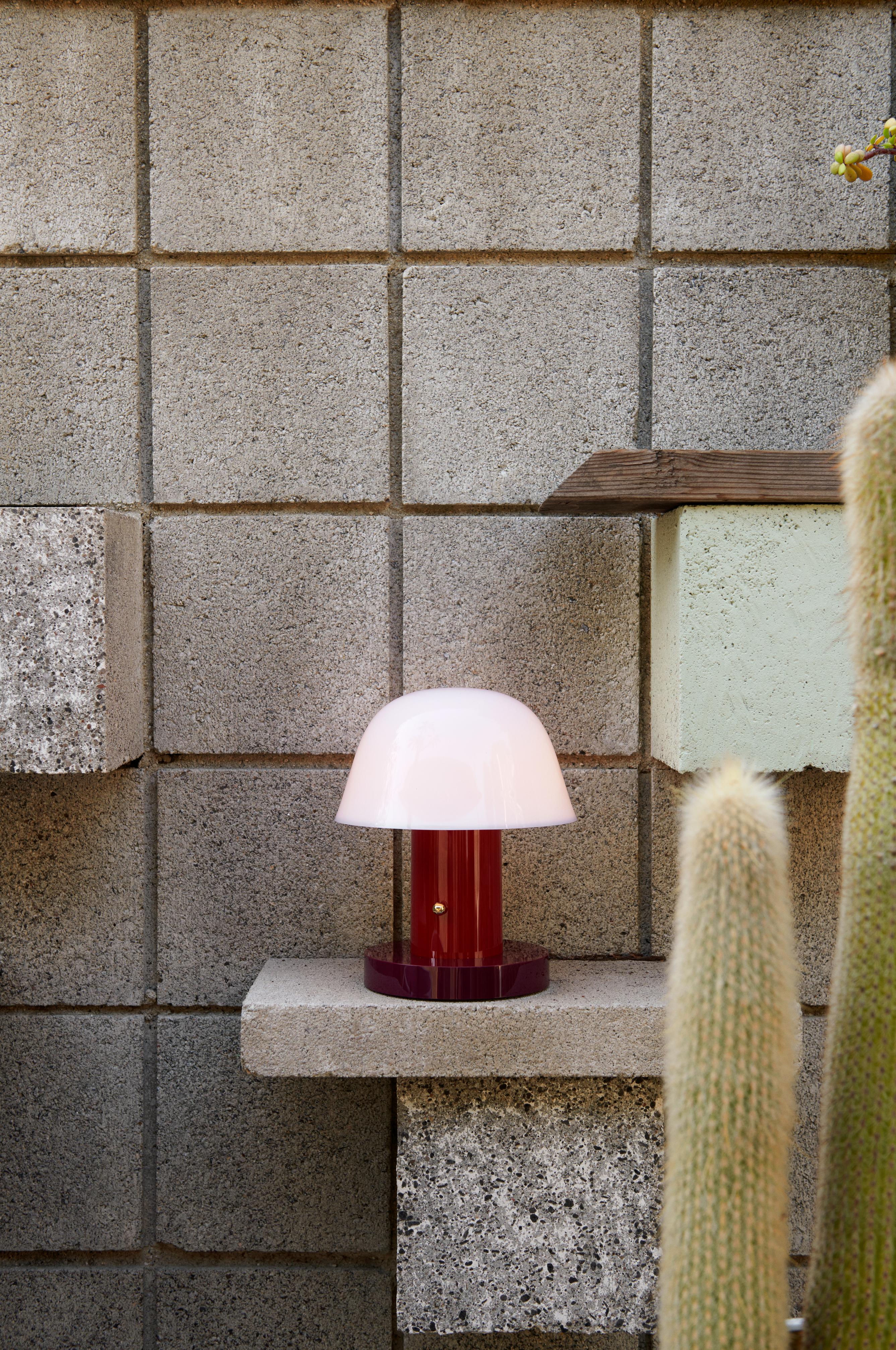 Draagbare lamp SETAGO JH27 met een crèmekleurige kap en een donkerrode voet.