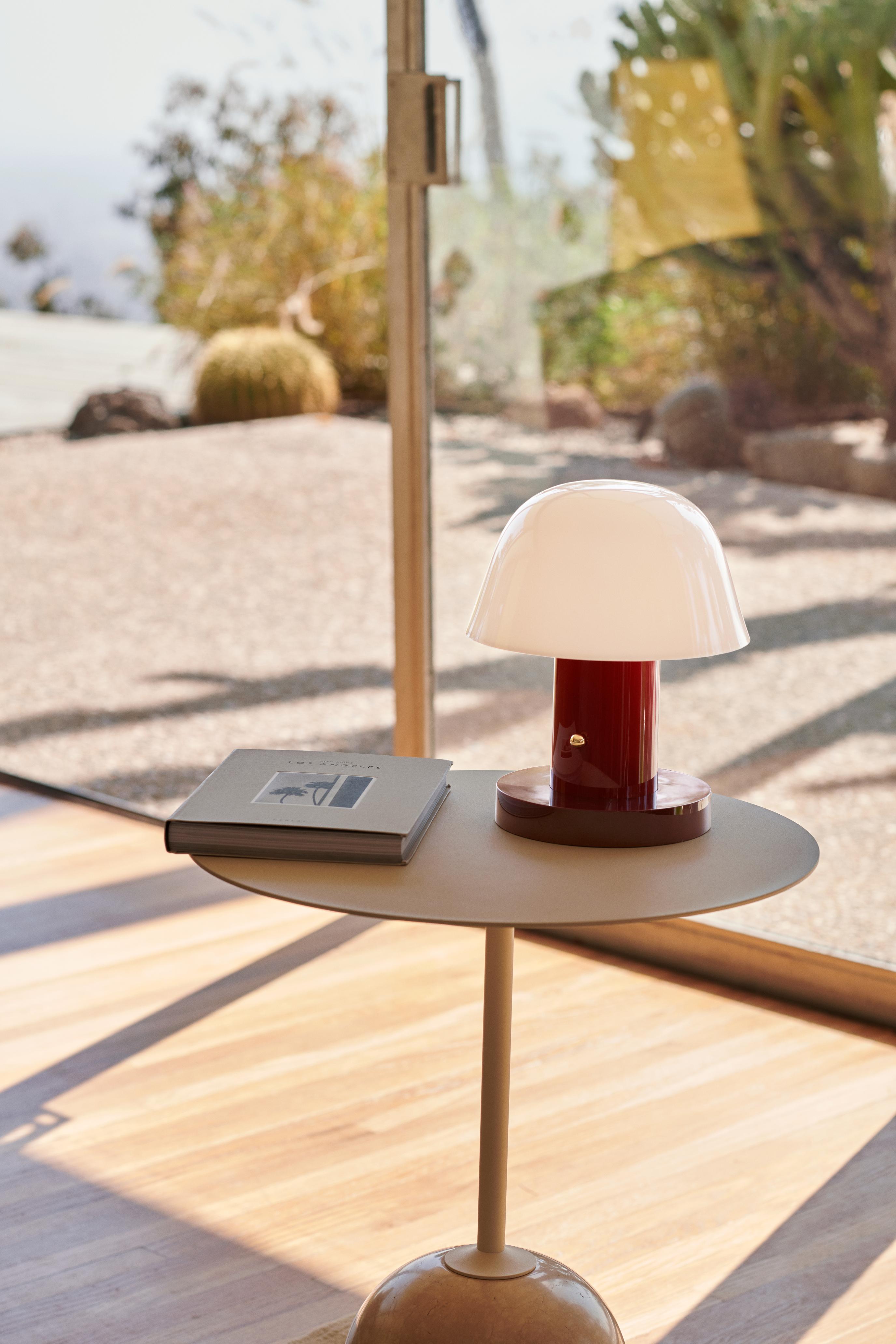 Draagbare lamp SETAGO JH27 met een crèmekleurige kap en een donkerrode voet.